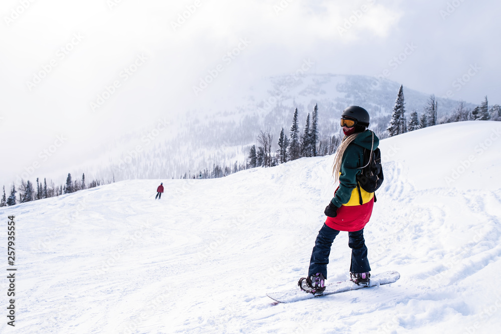 Girl with snowboard in the mountains on a snowy slope.