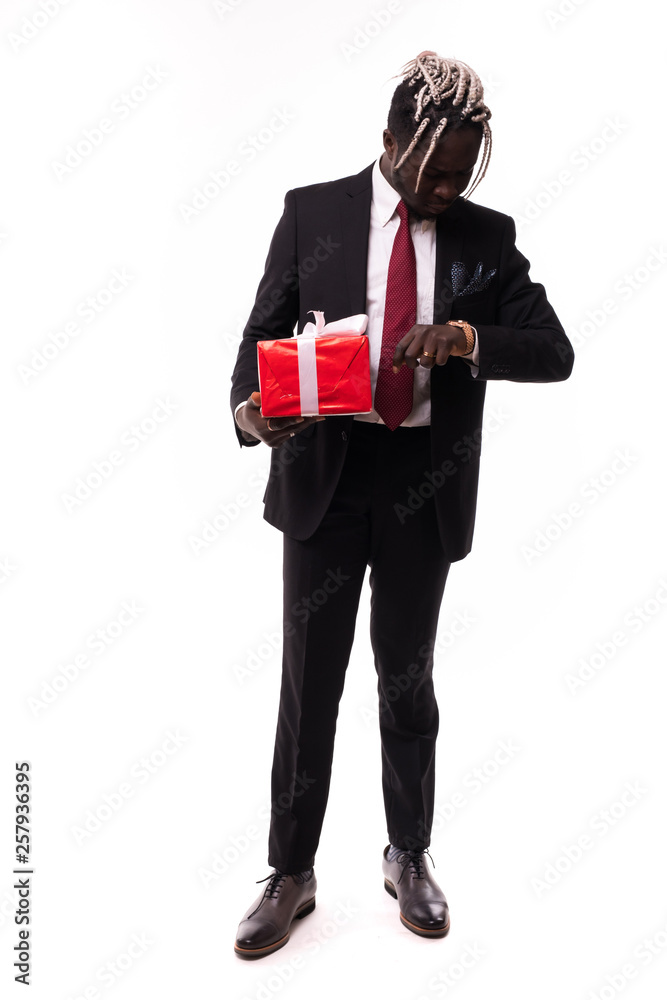 Young afro american businessman holding gift box and look at watch isolated on white background Young afro american businessman holding gift box and look at watch isolated on white background