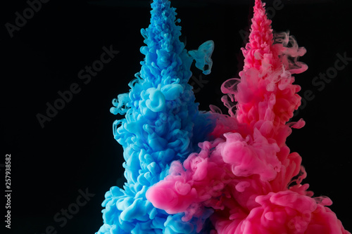 A cloud of colored acrylic paint in water. A drop of colorful ink dissolves in water on a black background. Abstract background.