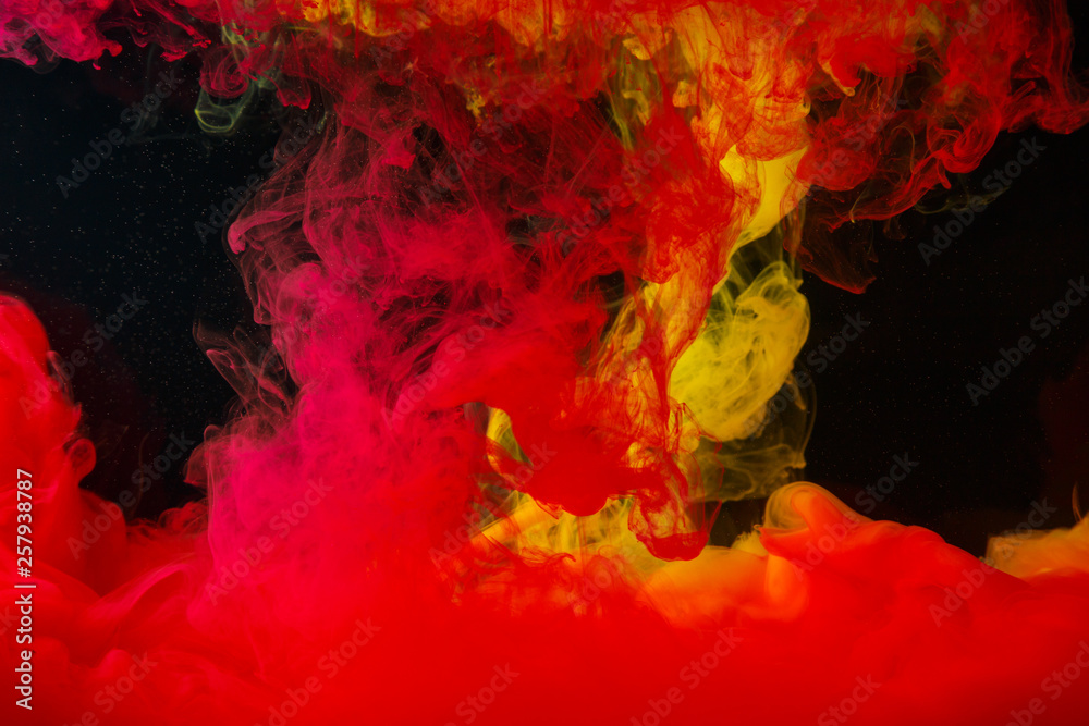 A cloud of colored acrylic paint in water. A drop of colorful ink dissolves in water on a black background. Abstract background. A cloud of colored acrylic paint in water. A drop of colorful ink dissolves in water on a black background. Abstract background.