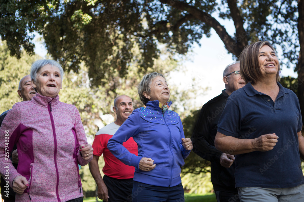 Anziana signora con i capelli grigi fa attività di Jogging in mezzo ad un parco Anziana signora con i capelli grigi fa attività di Jogging in mezzo ad un parco