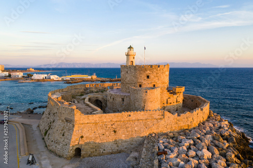 View of Fort of Saint Nicholas on Mandraki harbor during sunset photo