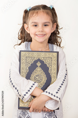 Happy young Muslim girl holding Holy Quran and wearing Islamic costume in Ramadan photo