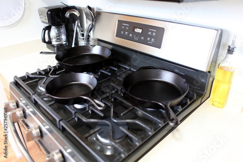 Modern stainless steel gas stove with cast iron skillets in a home kitchen.