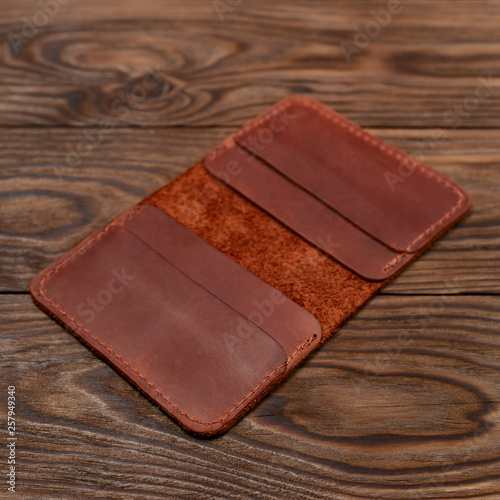 Handmade ginger colour leather cardholder on wooden background. Cardholder have 4 pockets for cards. Stock photo with soft focus background.