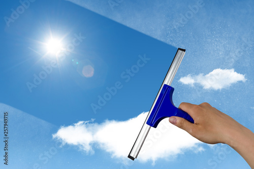squeegee cleaning a dirty window, spring cleaning concept, blue sky with copy space