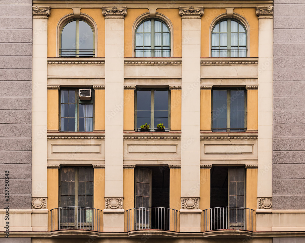 Obraz premium Several windows and balconies in a row on the facade of the urban historic building front view, Barcelona, Spain