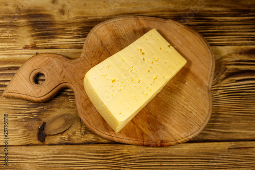 Piece of cheese on cutting board on wooden table