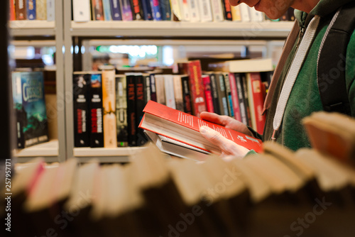 młody mężczyzna wybiera książkę w bibliotece photo