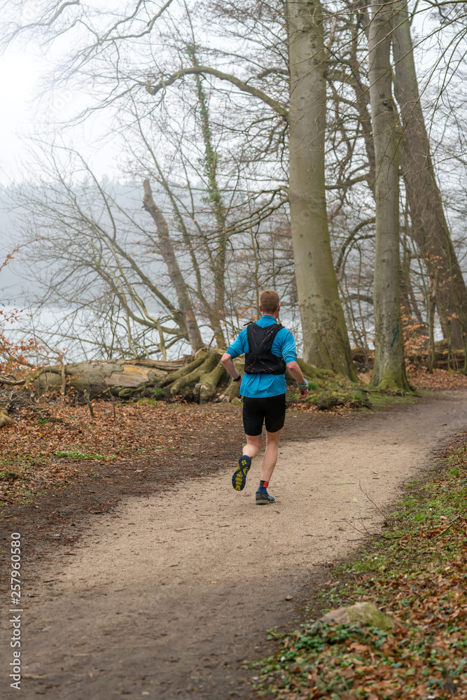 Athlete trailrunning through a forest in early spring Athlete trailrunning through a forest in early spring