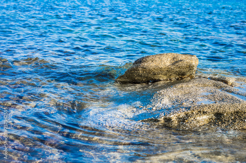 vivid blue shallow water natural reservoir near rocky shoreline with underwater stone outdoor beautiful background wallpaper pattern, copy space for text