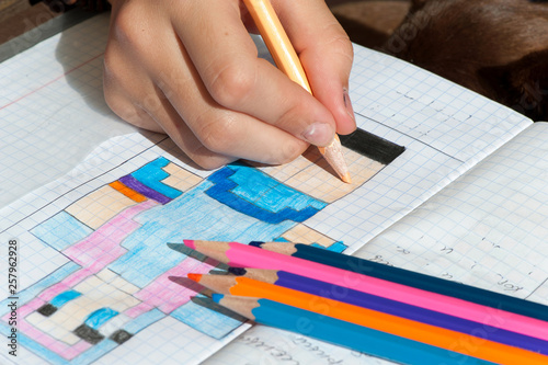 Child hand draws the multicolored minecraft picture.