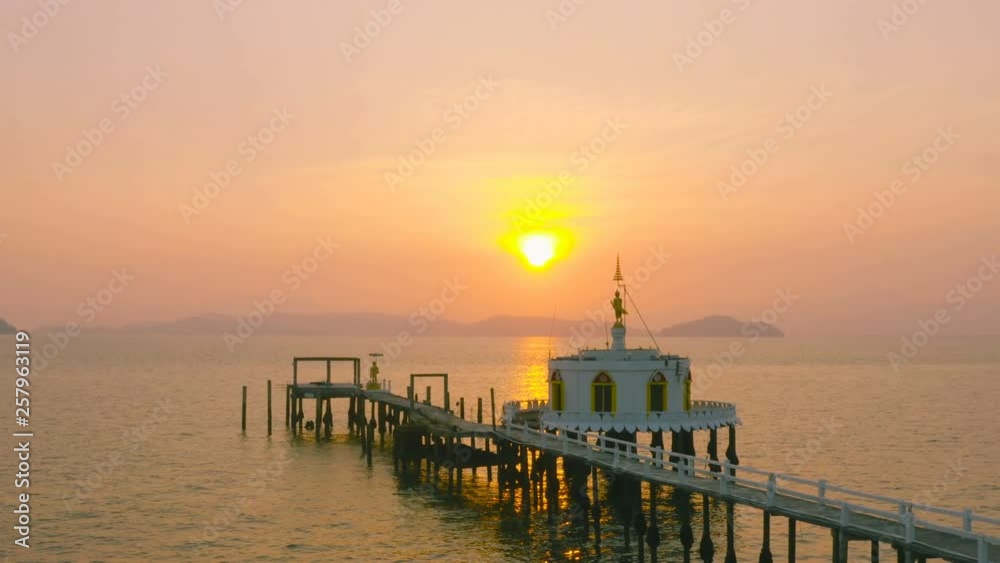 sunrise at standing golden Buddha on the pavilion in the sea. Phayam temple is a landmark of Phayam island. there have a long pier to go to pavillion in the sea