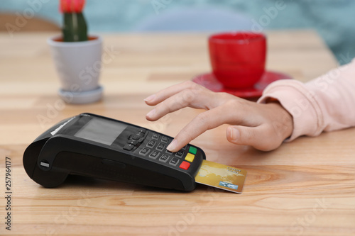 Woman using card machine for non cash payment at table, closeup photo