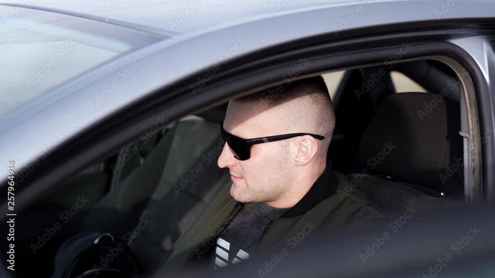 Side view of confident young stylish man in sunglasses driving his car Side view of confident young stylish man in sunglasses driving his car