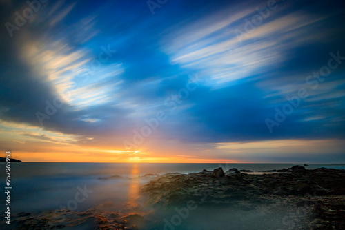 Fototapeta Naklejka Na Ścianę i Meble -  blue picture look of a sunrise on Fuerteventura Canarias in Spain. beautiful sea view, with rocks and soft clouds and water. great sunlight