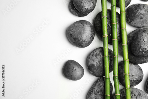 Wet zen stones and bamboo on white background, top view with space for text