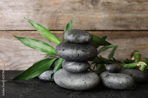 Stacked zen stones and bamboo leaves on table against wooden background