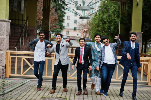 Group of six south asian indian mans in traditional, casual and business wear walking dancing and having fun together.