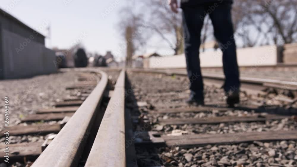 Man walking on train tracks, out of focus away from camera