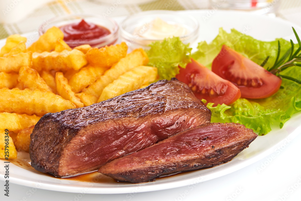 Grilled medium rare beef steak with french fries, sliced fried meat, close-up Grilled medium rare beef steak with french fries, sliced fried meat, close-up
