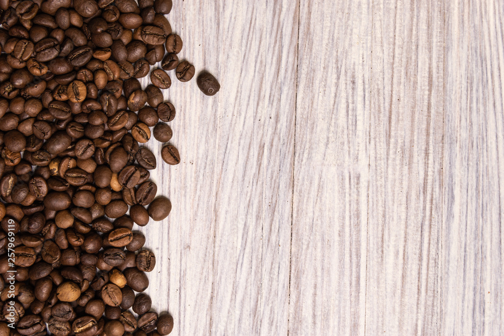 Roasted coffee beans in bulk on a light wooden background. dark cofee roasted grain flavor aroma cafe, natural coffe shop background, top view from above, copy space Roasted coffee beans in bulk on a light wooden background. dark cofee roasted grain flavor aroma cafe, natural coffe shop background, top view from above, copy space