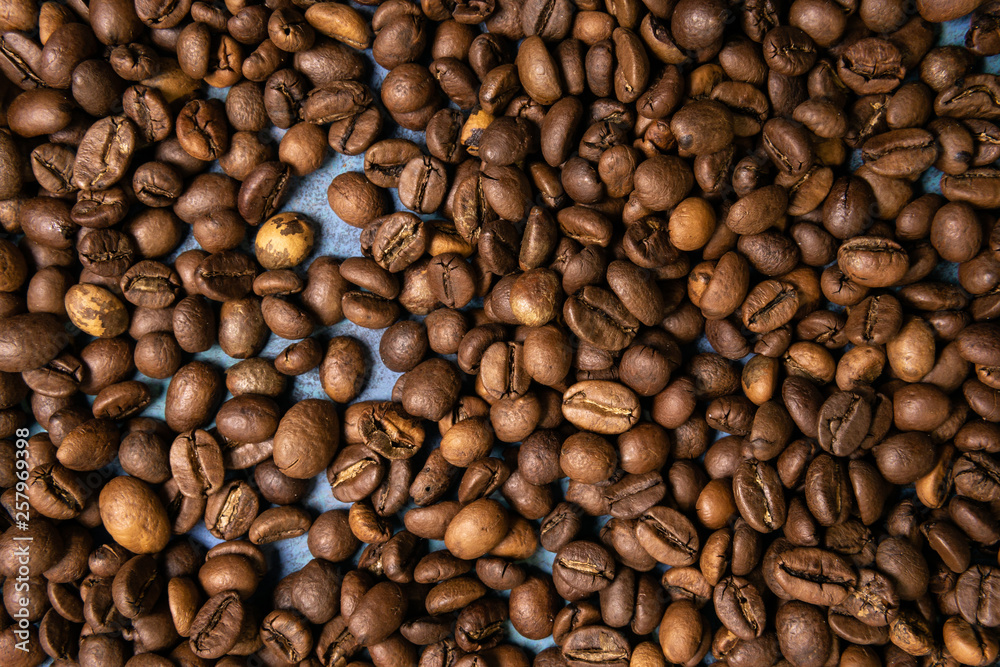 Obraz premium Roasted coffee beans in bulk on a blue background