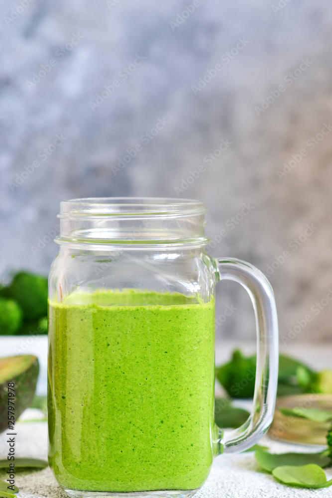 Green smoothie with spinach, avocado and broccoli on a concrete background.