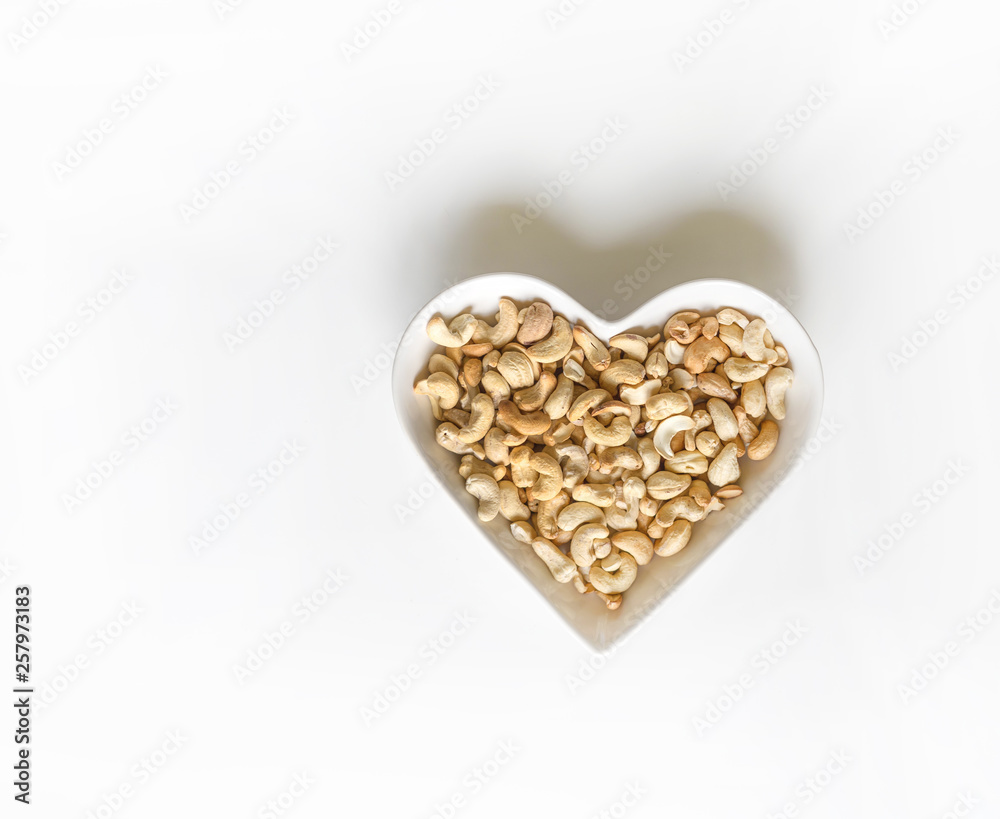 Nuts arranged in heart  on background. Healthy Food image close up cashew nuts. Love Texture on white grey table top view