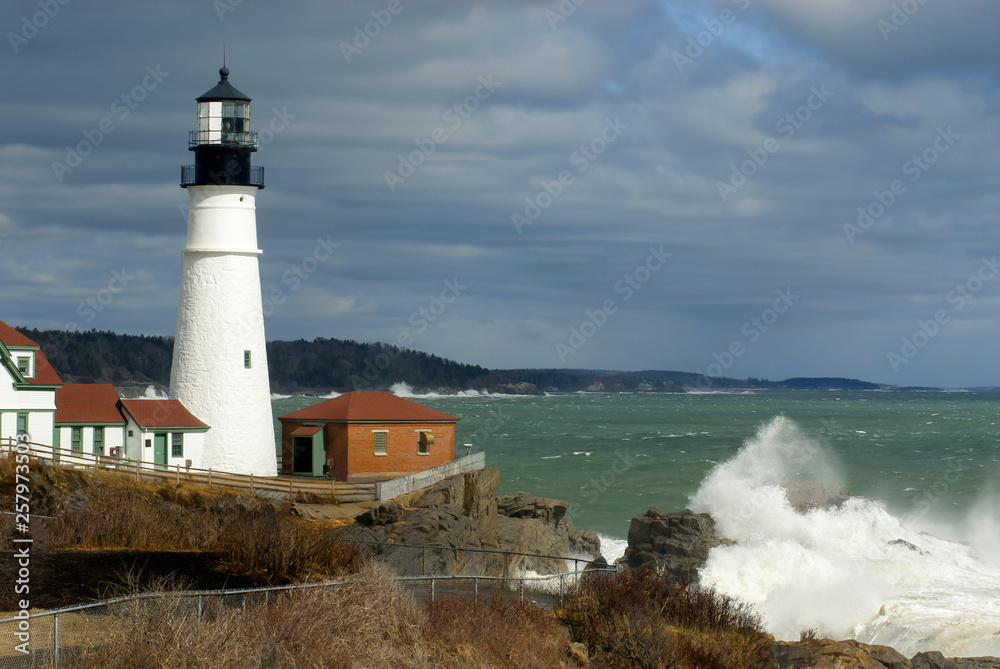Sunlight Breaks Through Clouds on Portland Head Lighthouse with Huge Waves Breaking in Maine