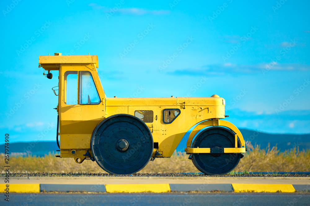 Selective focus side view of and old classic yellow steamroller / road  roller used as decoration in a roundabout of a highway in Spain Stock Photo  | Adobe Stock