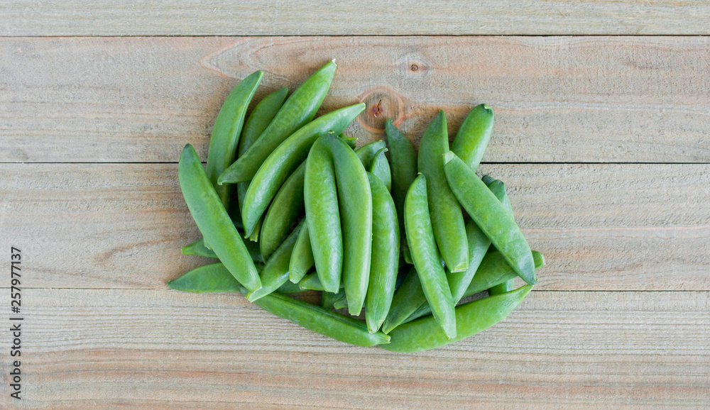 a small bunch of green sugar snap peas on a wood background viewed from above a small bunch of green sugar snap peas on a wood background viewed from above