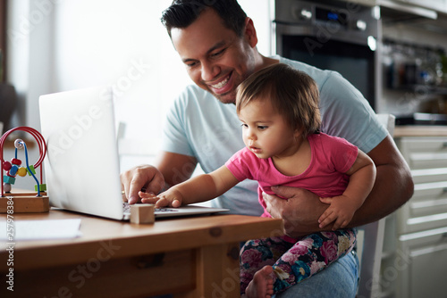 Smiling father and baby girl using laptop on table at home