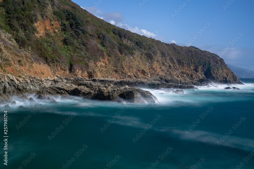 Long exposure of deep blue water, swirling surf, and rocky cliffs of central California Long exposure of deep blue water, swirling surf, and rocky cliffs of central California