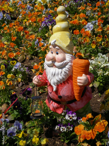 Garden figure of the gnome on the background of colorful flowers
