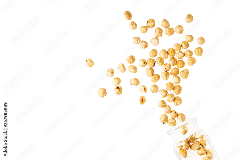 Close up, macro. A pile of hazelnut nuts flying out of a glass jar. Isolated on white background. Close up, macro. A pile of hazelnut nuts flying out of a glass jar. Isolated on white background.