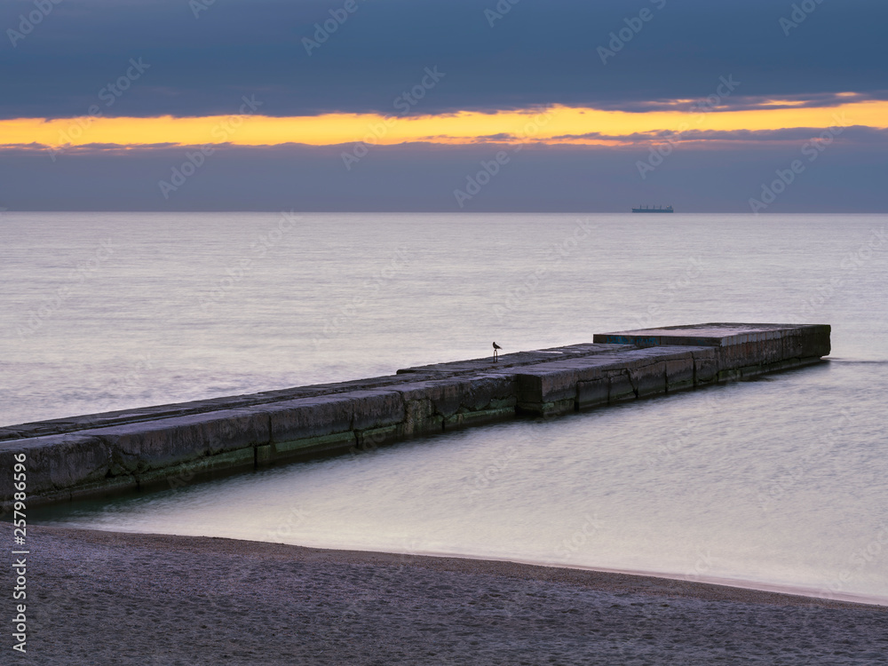pier and smooth water in the morning twilight with light line in clouds