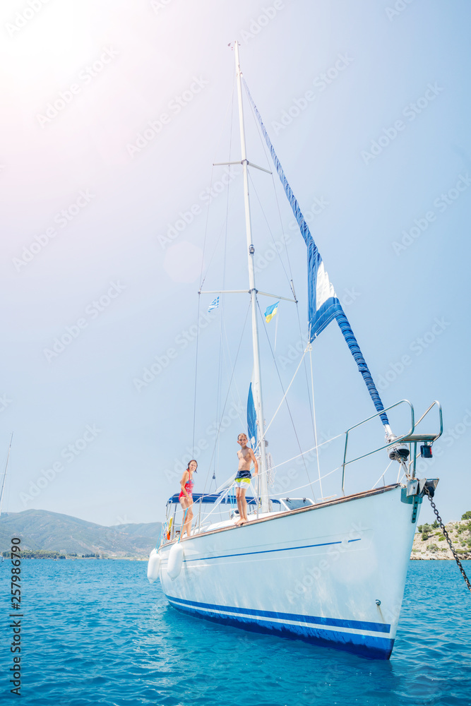 Boy jump in sea of sailing yacht on summer cruise. Travel adventure, yachting with child on vacation.