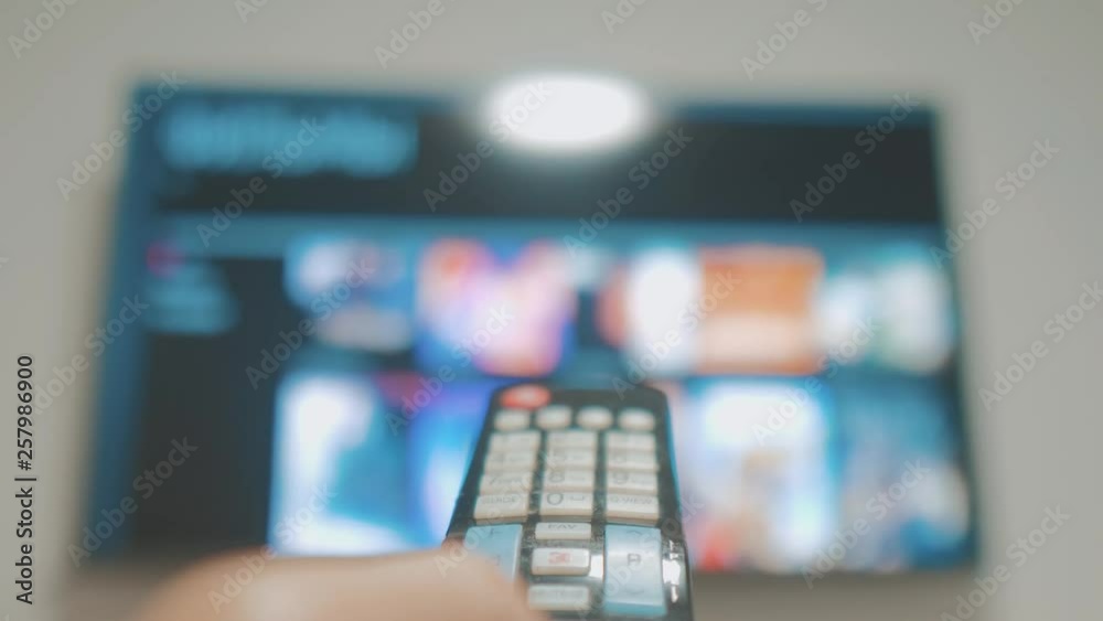 Smart tv with apps and hand. Male hand holding the remote control turn off smart tv. man hand lifestyle controls TV holding remote. concept internet online cinema Smart tv with apps and hand. Male hand holding the remote control turn off smart tv. man hand lifestyle controls TV holding remote. concept internet online cinema