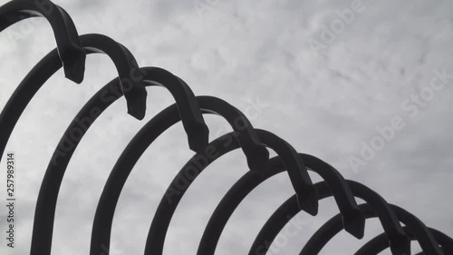 Metal fence with curved spikes and white clouds in the background