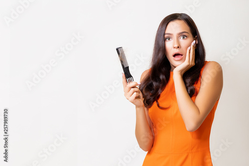 Hair fall problem. Young caucasian woman with comb and problem hair on white background. Beautiful girl looking hair loss from comb. Hair care and beauty concepts. - Image 