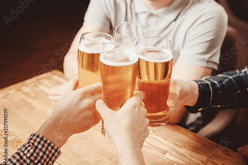 Irish pub. Guys clinking with beer mugs cheers photo