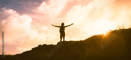silhouette of a man on top of the mountain with arms outstretched 
