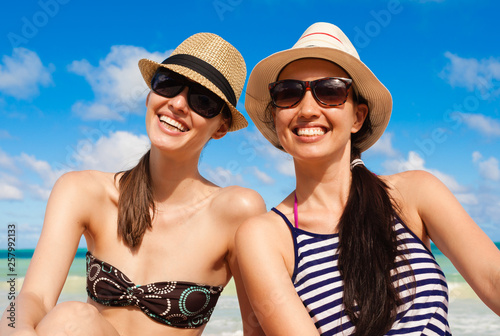 young happy teenaged girls in sunglasses on the beach