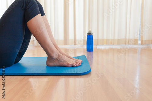 young woman doing fitness exercise on yoga mat