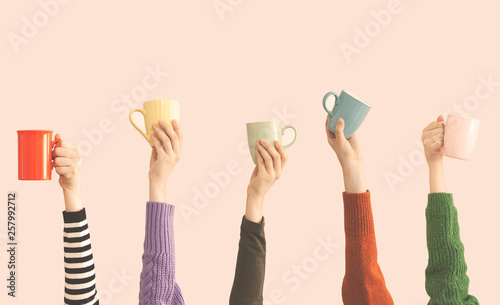 Many different arms raised up holding coffee cup photo