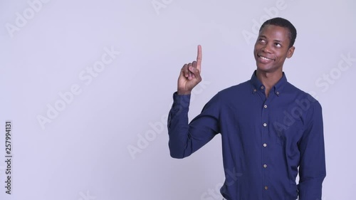 Young happy African businessman thinking and pointing up