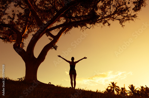 silhouette of a woman with arms up at sunset