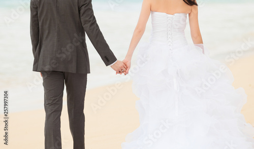 bride and groom holding hands on the beach