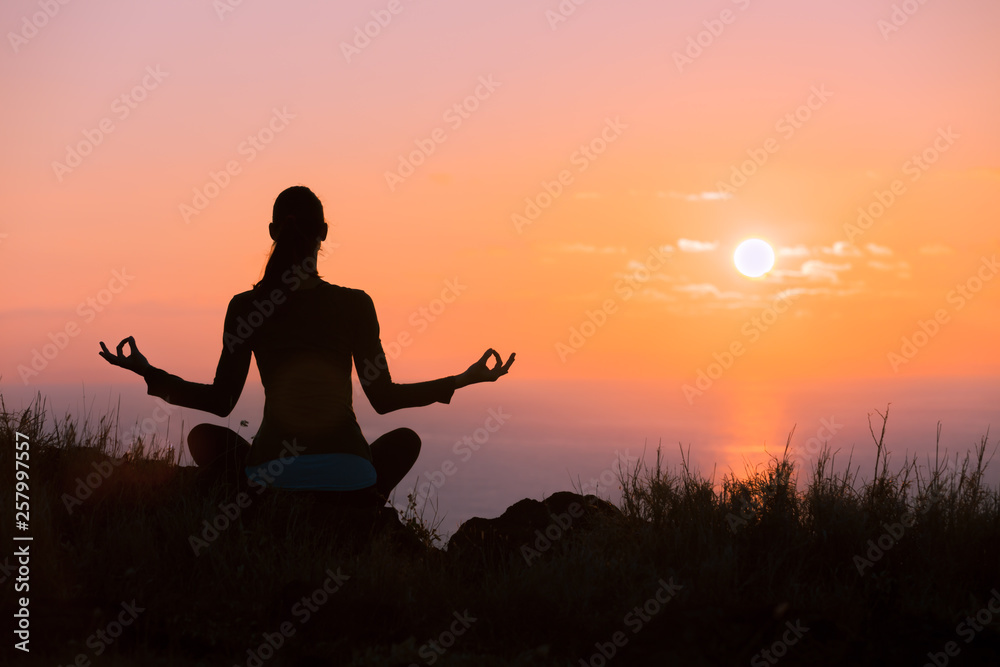 silhouette of young woman doing yoga at sunset